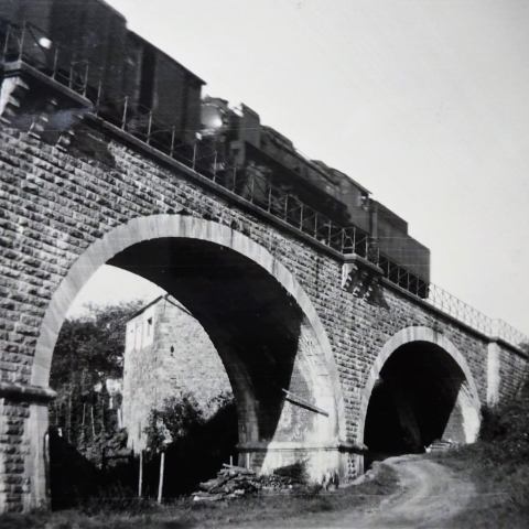 a large brick building with a bridge in the background