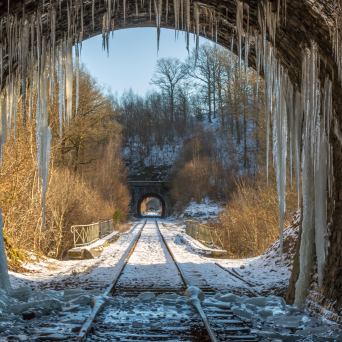 a waterfall with trees on the side of a snow covered bridge