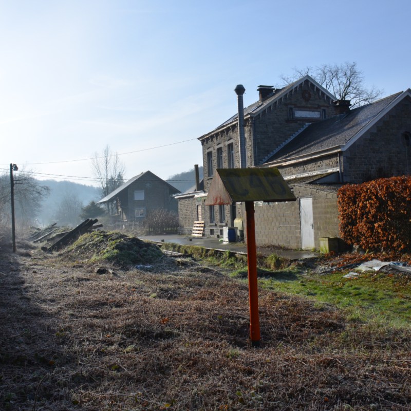 a house that has a sign on the side of a dirt field