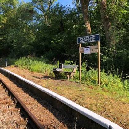a sign located on a train track with trees in the background