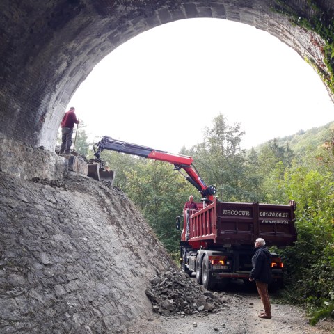 a person riding on the back of a truck traveling down a dirt road