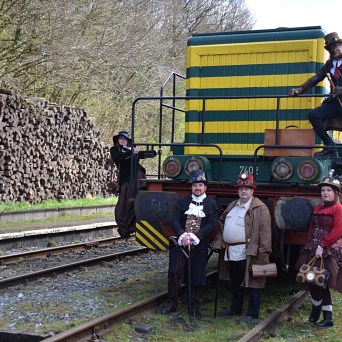a group of people sitting on a train track near a fence