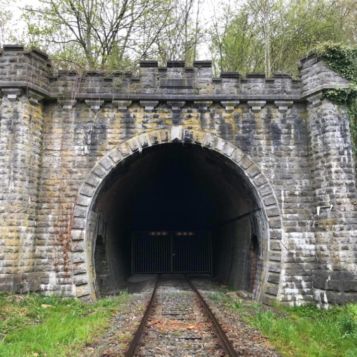an old stone building with Staple Bend Tunnel in the background