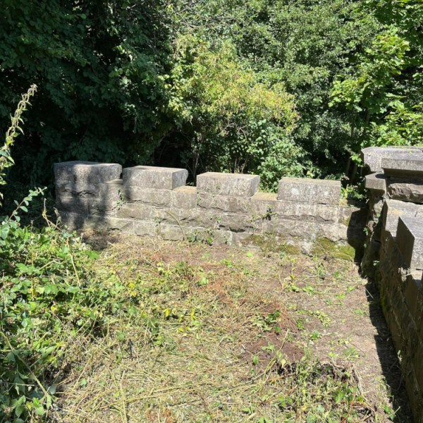 a stone building with grass and trees