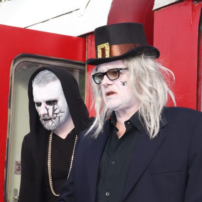 a man wearing a hat and sunglasses standing outside of a building