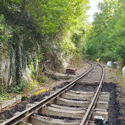 Railway track under construction, surrounded by lush greenery and a worker in the distance.
