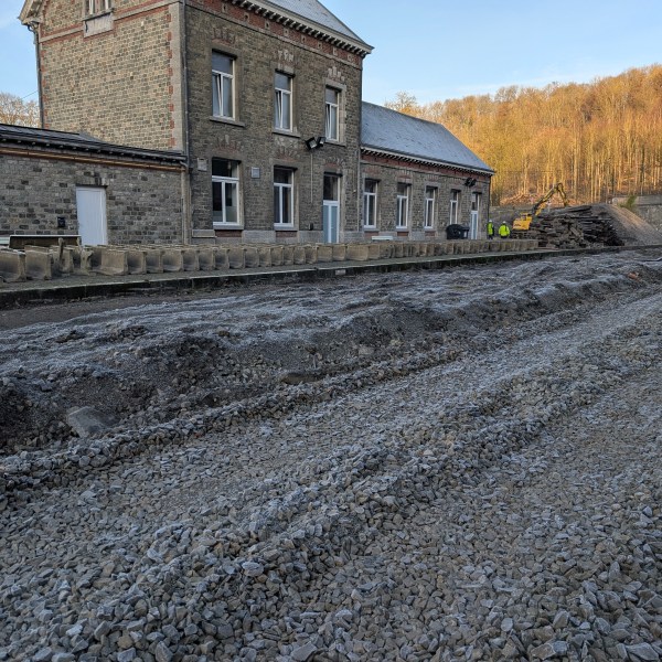 Old train station with tracks under construction, gravel piled up, tunnel entrance visible in the background.