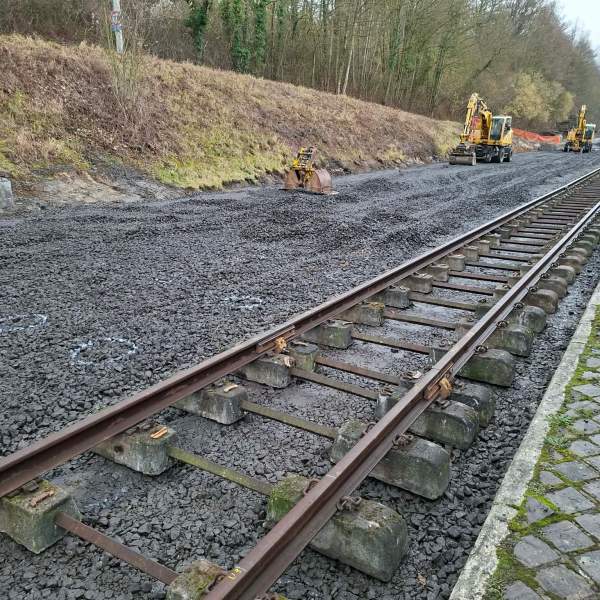 Railway track under construction with machinery and gravel.