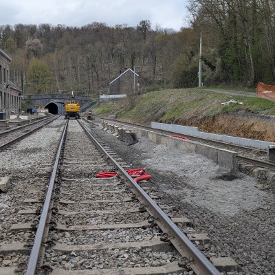 Railway tracks leading to a tunnel, with construction equipment on the left.