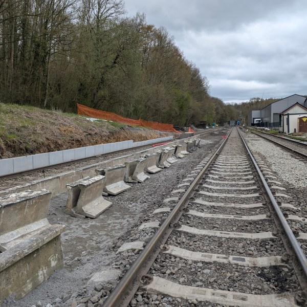 Railway construction site with parallel tracks and overhead cloudy sky.