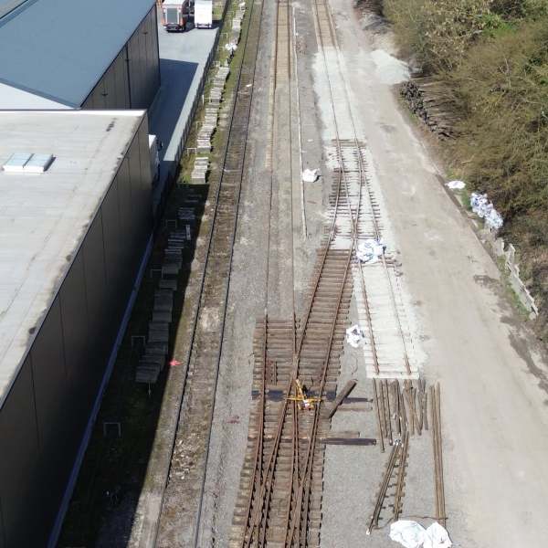 Aerial view of railway tracks alongside industrial buildings and trees.