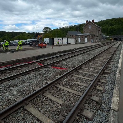 Railway tracks at a rural station with construction work and equipment nearby.