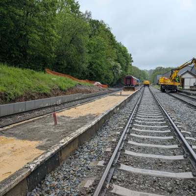 Railway tracks beside a construction area with trees in the background.