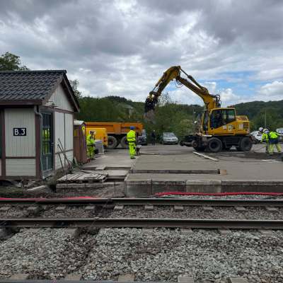 Construction crew working near railway tracks with an excavator.