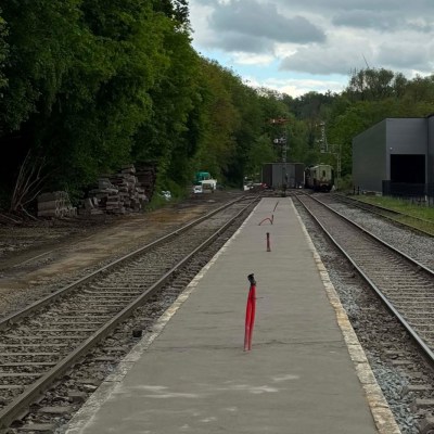 Railway tracks surrounded by trees and clouds in sky.