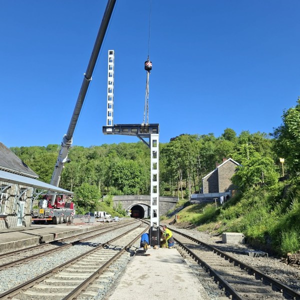Railway station with crane installing signal tower beside tracks.