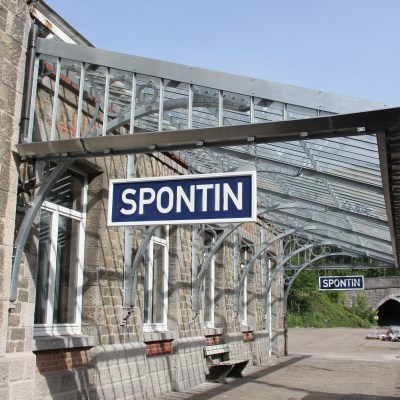 Spontin train station with glass canopy and visible tunnel entrance.