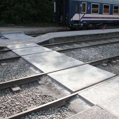 Railway tracks with a pedestrian crossing and a train in the background.