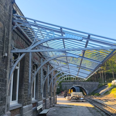 Railway station with glass canopy and train track leading into a tunnel.