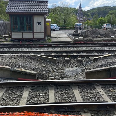 Train tracks with a small building and cloudy sky in the background.