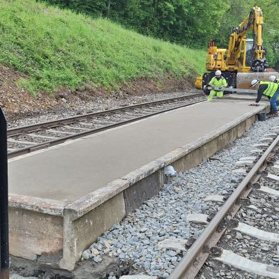 Construction workers building a platform between two railway tracks.