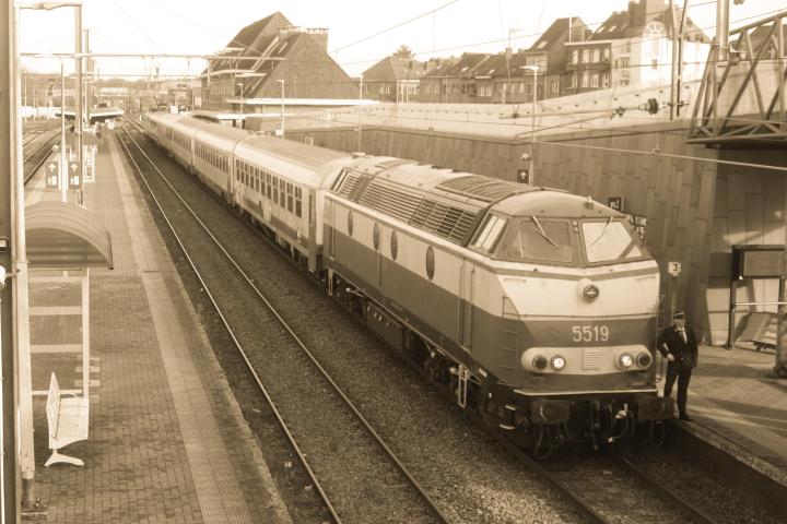 Sepia-toned image of a train at a station with several passenger cars.
